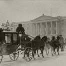 Fra utstillingen "Den kongelige stall. Hestehold og ekvipasjer". 1932: Kroningsvognen på vei tilbake til Slottet etter et besøk på Stortinget en januardag i 1932. Hestene er ikledt seletøy dekortert med riksløven, mens kuskene er iført bjørneskinnsluer og kjørepels. Bildet er kun til redaksjonell bruk - ikke for salg. Foto: Carsten Sætren, De kongelige samlinger.